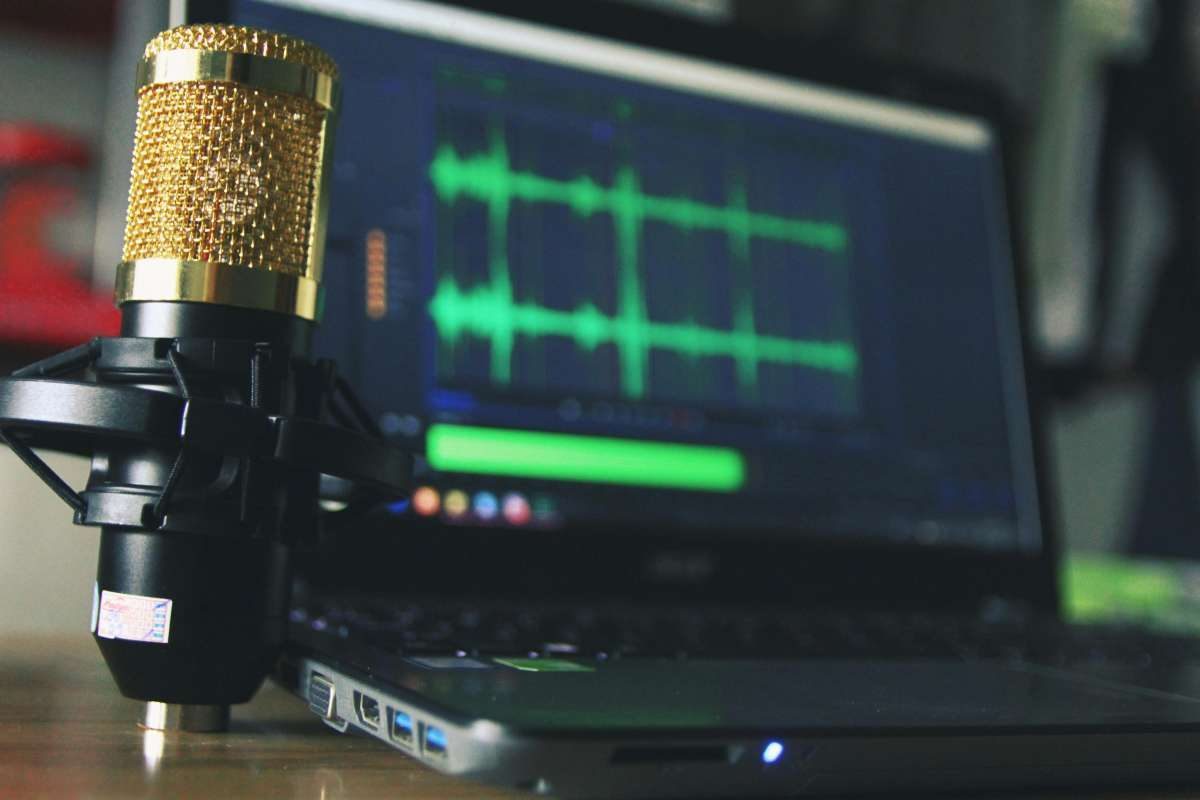 Mikrofon und Laptop mit Audiospur beim Podcast-Schnitt